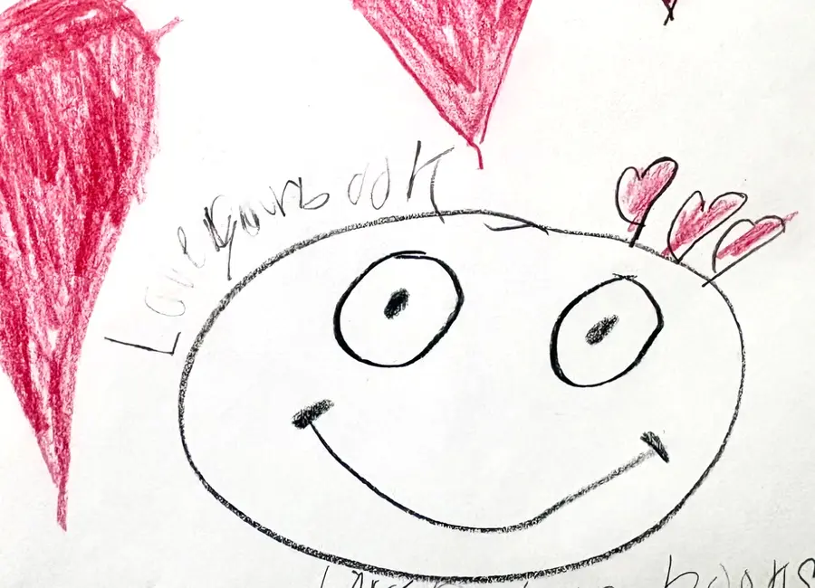 A student's drawing of red hearts and a smiling face